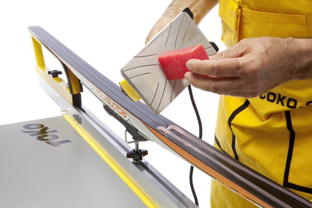 Ski tech is waxing a ski with base performance red hot wax.